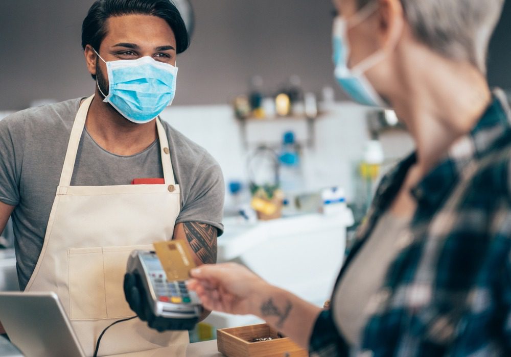 masked employees making a transaction with a masked customer via credit card 