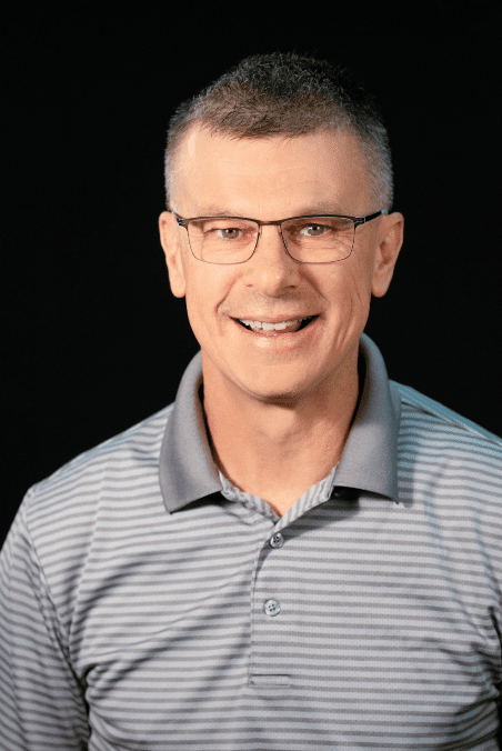 Steve Webb headshot - man wearing glasses and collared shirt smiling for camera. 